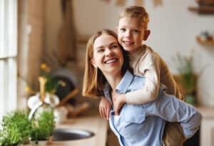 A joyful woman giving a piggyback ride to a cheerful boy while they play together at home, with heating and cooling.